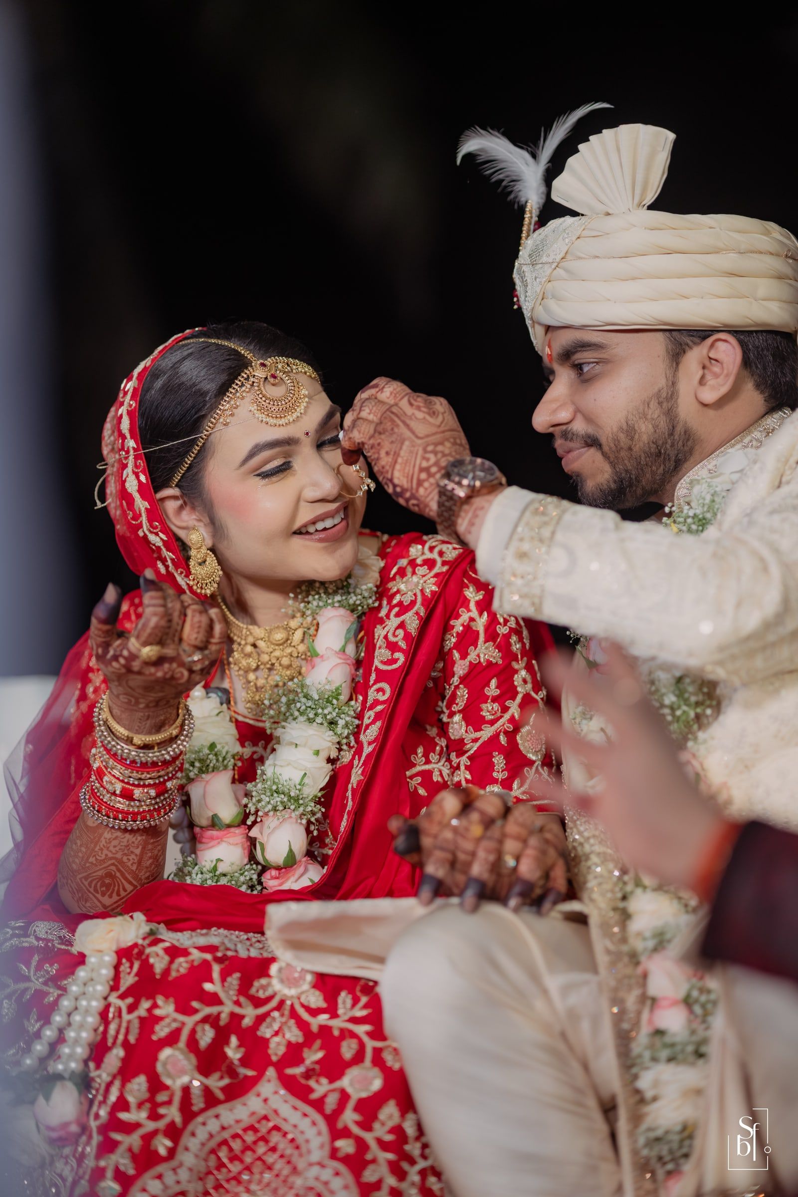 Bride and groom sharing a tender moment in red and ivory wedding attire