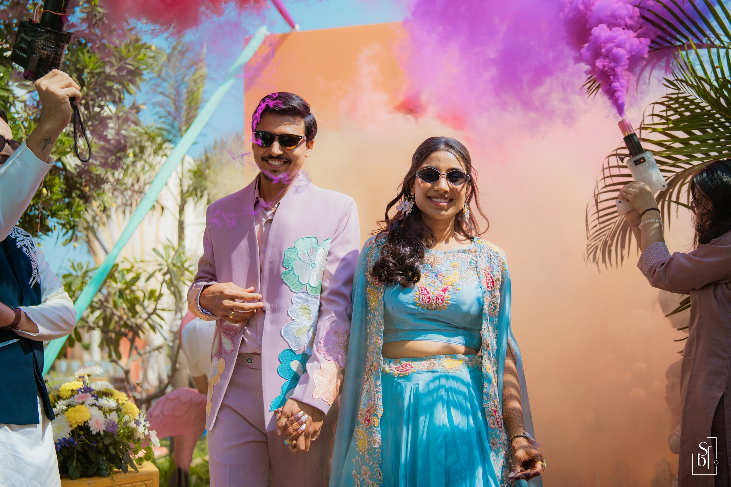 Couple walking through clouds of colour during a joyful celebration